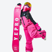 
                  
                    Kids snowboard jacket bibs and pants combo - pink kids bibs, action pose holding snowboard, for cold-weather winter sports
                  
                