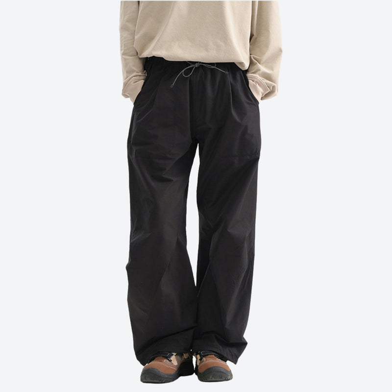 Water-repellent nylon hiking pants with relaxed fit - black wide-leg hiking pants with cream top, front standing view