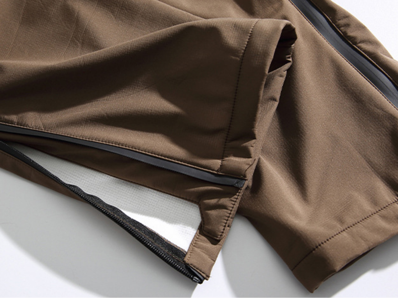Men's warm fleece-lined cargo pants with belt - brown, hem zip open close-up from side angle, for hiking and trail walking