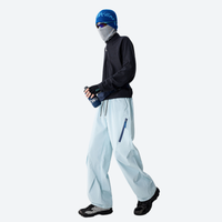 
                  
                    Unisex waterproof 2-in-1 down pants with liner - ice blue down pants with black top and blue beanie, walking view
                  
                