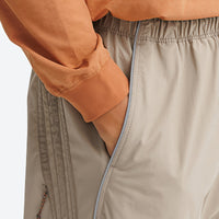
                  
                    Unisex lightweight outdoor cargo pants - tan, waist pocket close-up with hand, for camping and travel
                  
                