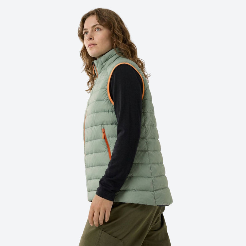 Lightweight down jacket and vest collection - sage green down vest on women, side standing view, for layering in cold weather