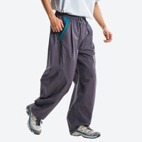 
                  
                    Breathable relaxed trail pants with drawcord waist - dark gray quick-dry hiking pants with blue top, stride walking view
                  
                