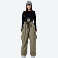 
                  
                    Unisex waterproof 2L asymmetric snow jacket - tan snow pants with black top, for cold-weather winter sports
                  
                