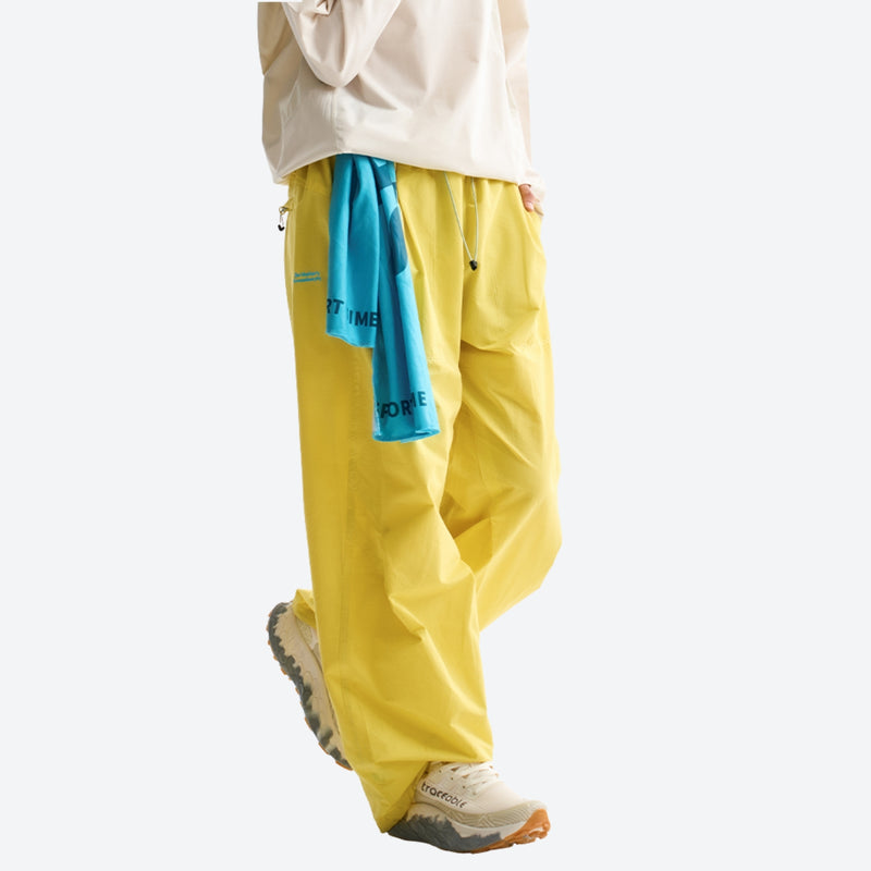 Water-repellent nylon hiking pants with relaxed fit - yellow wide-leg hiking pants with blue waist cloth, walking side view