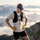 Trail gloves with touchscreen fingertips and grip palm - mustard merino wool hiking gloves on men, mountain standing view