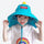 Kids wide brim sun hat with whistle drawstring - teal dinosaur kids sun hat on girl, worn front view, for park days in summer