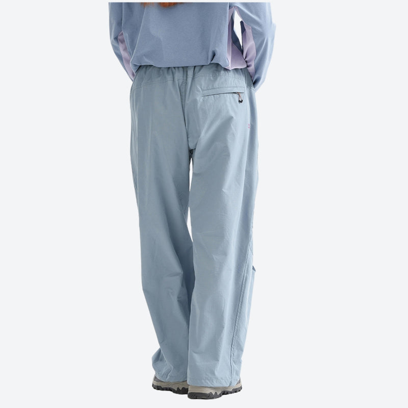 Water-repellent nylon hiking pants with relaxed fit - light blue wide-leg hiking pants with blue top, back standing view