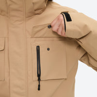 
                  
                    Men's 2-layer snowboard jacket and bib pants - tan jacket, chest zip close-up with hand, for resort and backcountry days
                  
                