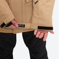
                  
                    Men's waterproof 2L snow jacket and suspender pants - tan jacket, hem cinch close-up with hand, for powder and piste riding
                  
                