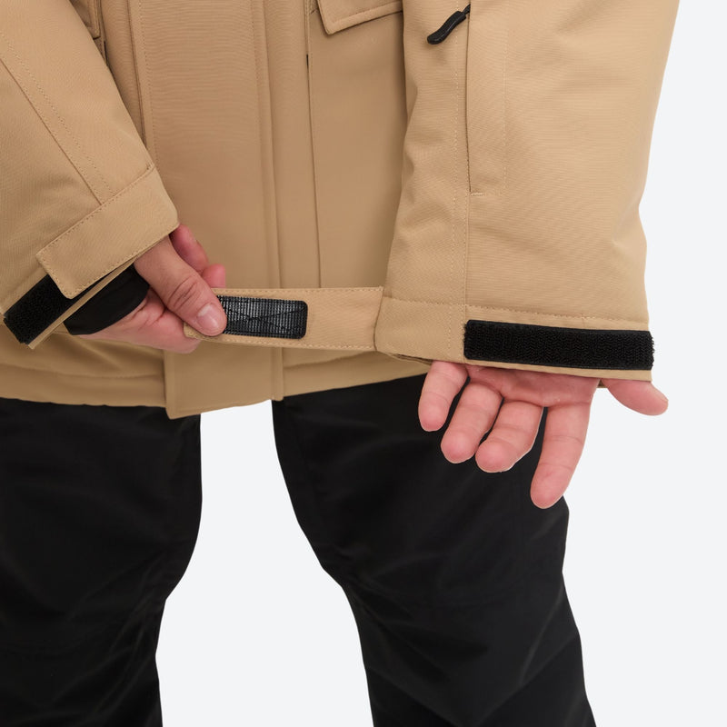 Men's waterproof 2L snow jacket and suspender pants - tan jacket, hem cinch close-up with hand, for powder and piste riding