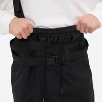 
                  
                    Unisex bib snowboard pants with snow gaiters - black, waistband buckle close-up with both hands, for skiing and snowboarding
                  
                