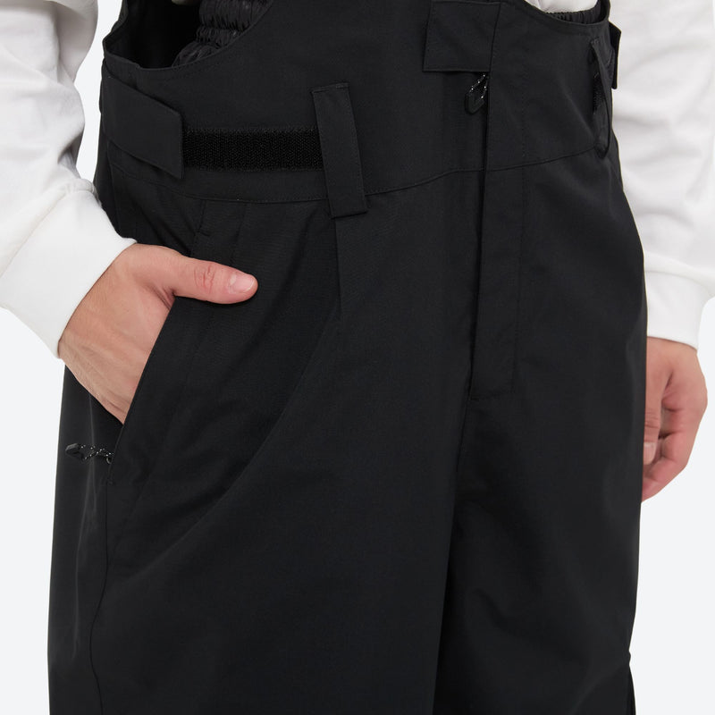 Unisex bib snowboard pants with snow gaiters - black, side pocket close-up with hand, for cold-weather winter sports
