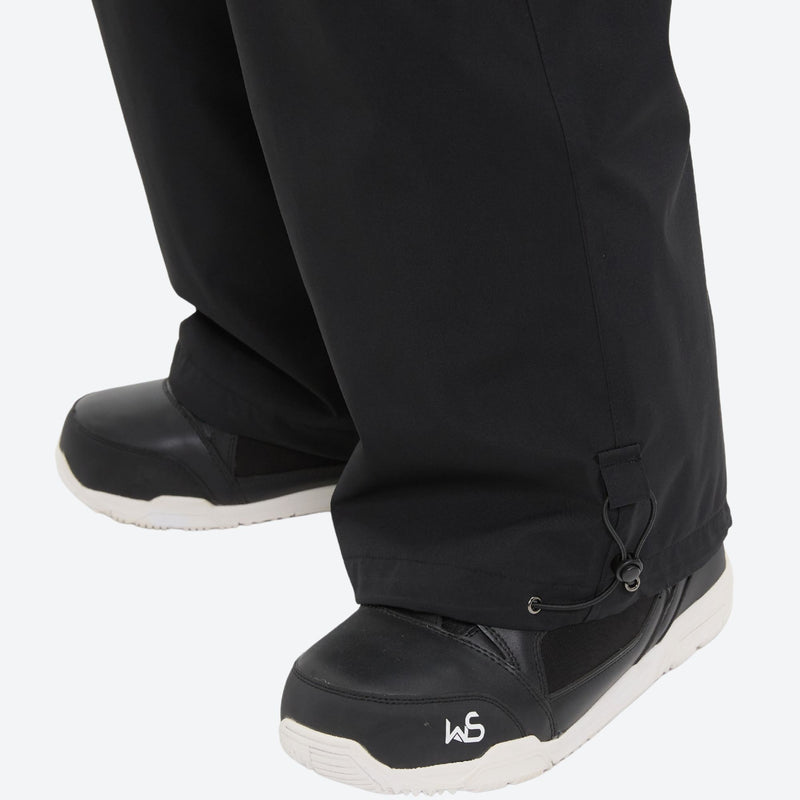 Unisex bib snowboard pants with snow gaiters - black, hem over boot close-up detail, for powder and piste riding