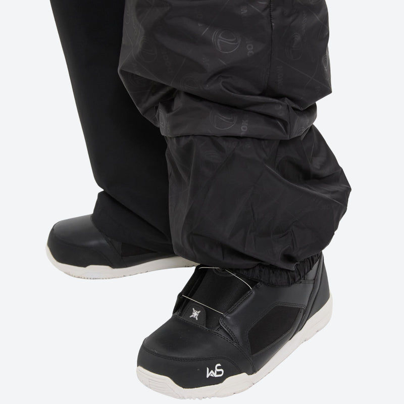 Unisex waterproof 3L bib snow pants - black, hem gaiter over boot side close-up detail, for cold-weather winter sports