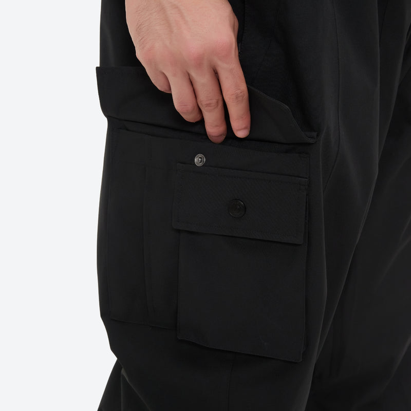 Men's 3-layer snowboard jacket and pants - black snow pants, cargo pocket close-up with hand, for skiing and snowboarding