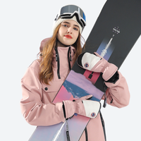 
                  
                    Blizzard snow mittens with three layer warmth - pink snow mittens on women in pink jacket with snowboard, front standing view
                  
                