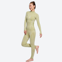 
                  
                    Warm merino wool baselayer suit for snow sports - khaki merino compression base layer suit on women, one-leg standing view
                  
                