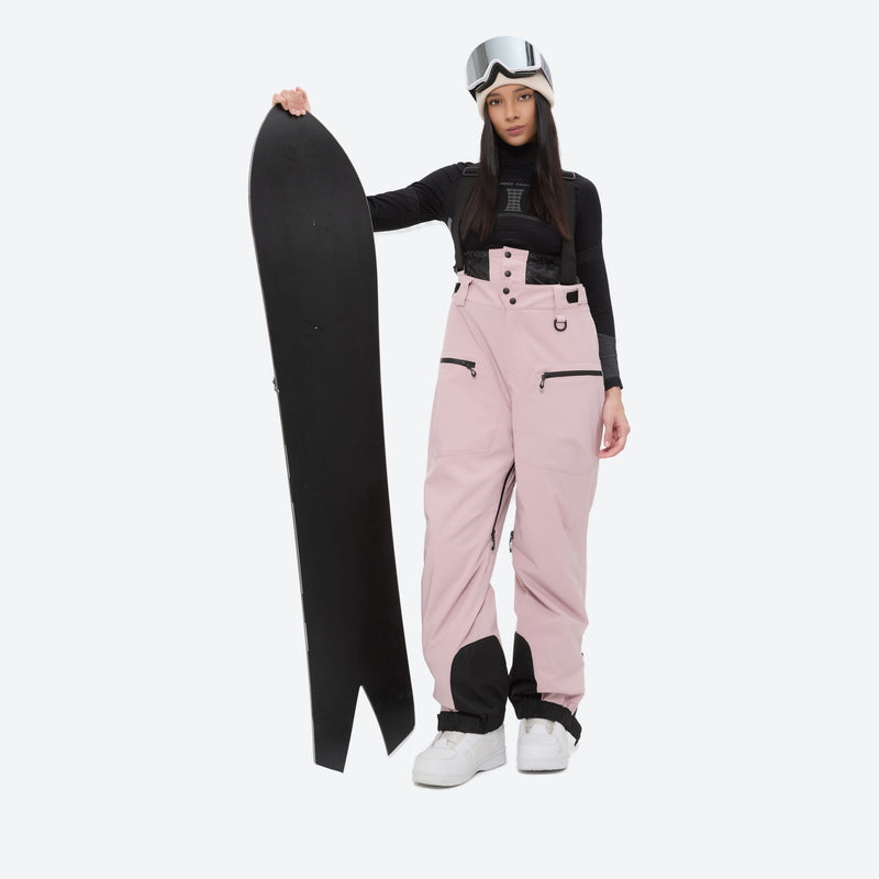 Insulated bib snow pants for women - pink bib pants, on-model front with upright snowboard, for cold-weather winter sports