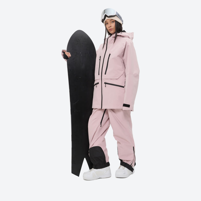 Women's 3L waterproof suspender snow pants - pink, on-model front with upright snowboard, for skiing and snowboarding