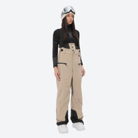 
                  
                    Insulated bib snow pants for women - tan bib pants, on-model front view, for cold-weather winter sports
                  
                