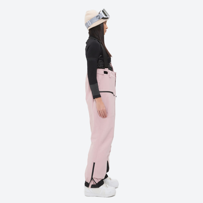 Women's adjustable ski pants with suspenders - pink bib pants, on-model side view, for skiing and snowboarding