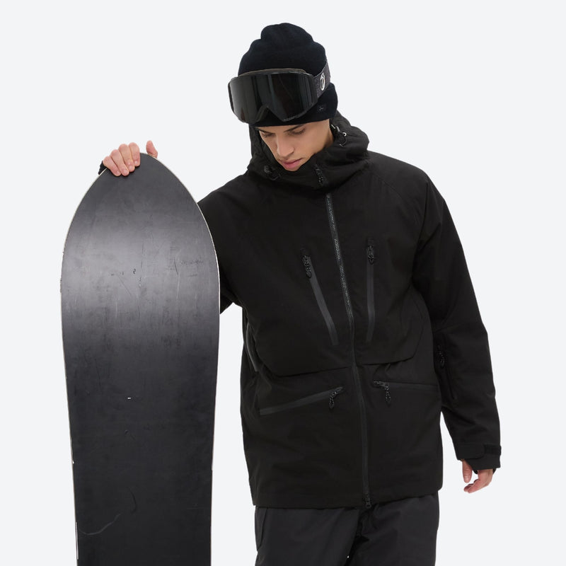 Men's adjustable ski pants with suspenders - black, on-model front with upright snowboard, for deep powder winter days