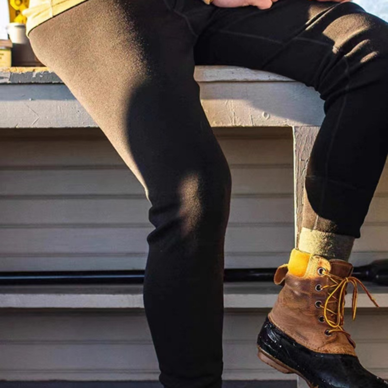 Men's soft merino wool baselayer leggings for cold days - black merino wool thermal pants with boots, on-feet sitting view