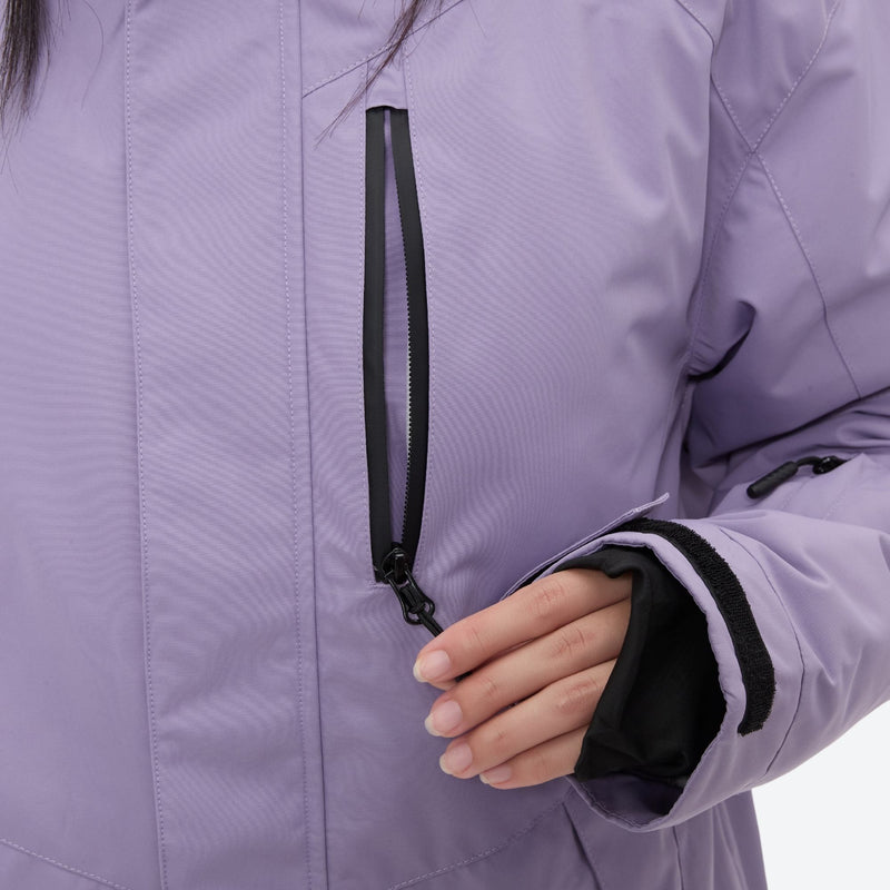 Women's waterproof 2L ski jacket and bib pants - lavender, chest pocket zip close-up with hand, for snowy mountain travel