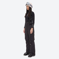 
                  
                    Women's breathable ski jacket with suspender pants - black snow pants, on-model side view, for skiing and snowboarding
                  
                