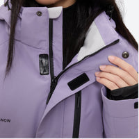 
                  
                    Women's waterproof 2L ski jacket and bib pants - lavender, chest zip close-up with hand, 2-layer waterproof breathable shell
                  
                