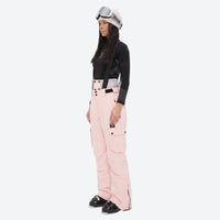 
                  
                    Women's waterproof 2L ski jacket and bib pants - light pink snow pants, on-model side view, for snowy mountain travel
                  
                