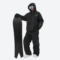 
                  
                    Breathable ski jacket and snow pants combo - black, on-model front with upright snowboard, for skiing and snowboarding
                  
                