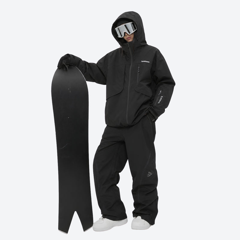 Breathable ski jacket and snow pants combo - black, on-model front with upright snowboard, for skiing and snowboarding