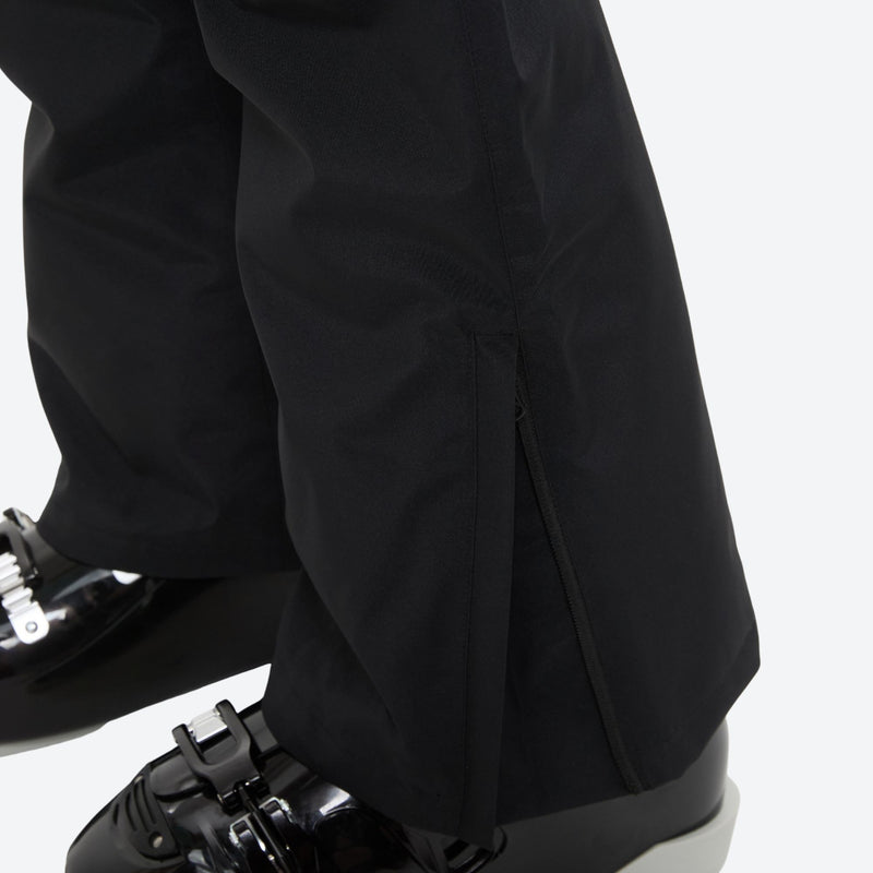 Unisex snowboard bib pants with snow gaiters - black, hem snow gaiter over boot close-up detail, for powder and piste riding