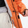 Unisex 2-layer snowboard jacket and pants - orange jacket, hem cinch close-up with hand, for skiing and snowboarding