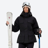 
                  
                    Women's belted snow jacket with suspender pants - black, front with upright skis and poles, for cold-weather winter sports
                  
                