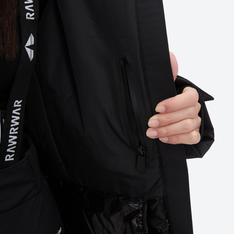 Women's belted snow jacket with suspender pants - black, chest zip close-up with hand, for resort and cross-country days