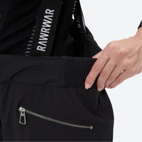 
                  
                    Women's 3-layer snowboard jacket and bib pants - black, waistband zip close-up with hand, for powder and piste riding
                  
                