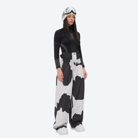 
                  
                    Women's minimalist breathable ski jacket set - cow print snow pants, on-model side view, for resort and street wear
                  
                