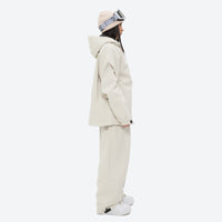 
                  
                    Women's waterproof 2L snow jacket and pants - cream jacket with cream pants, on-model side view, for resort and street wear
                  
                