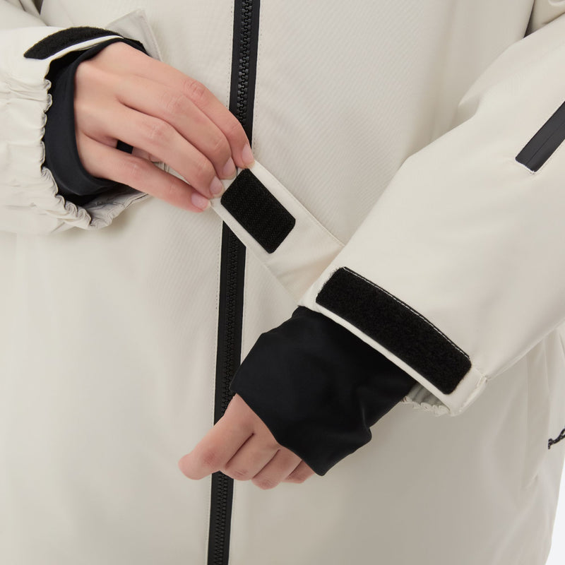 Women's 2-layer snowboard jacket and pants - cream, cuff strap close-up with hand, for resort and street wear