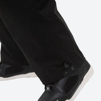 
                  
                    Men's 2-layer snowboard jacket and pants - black snow pants, hem cinch over boot close-up detail, for resort and street wear
                  
                