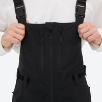 
                  
                    Unisex waterproof 3L bib snow pants - black bib pants, bib chest zip close-up with hand, for cold-weather winter sports
                  
                
