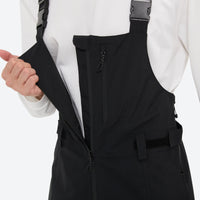 
                  
                    Unisex snowboard bib pants - black bib pants, bib side zip open close-up with hand, for skiing and snowboarding
                  
                