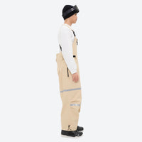 
                  
                    Unisex waterproof 3L bib snow pants - tan bib pants with white top, on-model side view, for skiing and snowboarding
                  
                