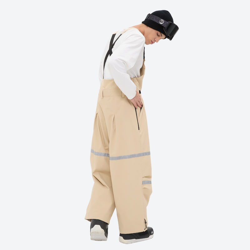 Unisex waterproof 3L bib snow pants - tan bib pants with white top, side view bending forward, for cold-weather winter sports