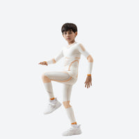 
                  
                    Kids compression base layer suit - cream kids compression base layer suit, leg-raise pose view, for layering under ski wear
                  
                