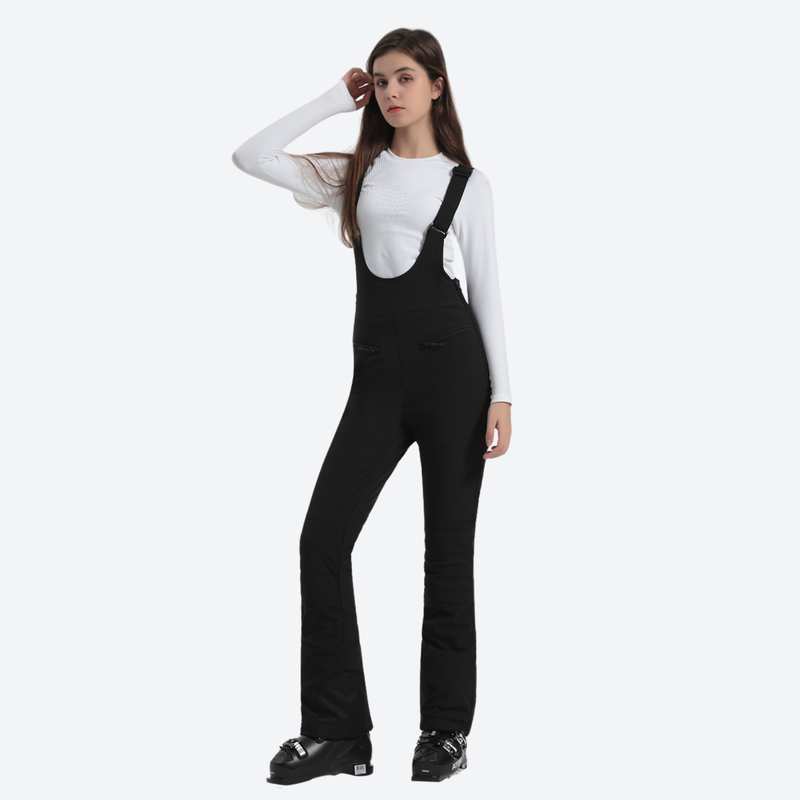 Women's slim fit waterproof ski bib pants - black slim fit ski bib, front view with hand at cap, for resort ski days