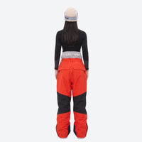 
                  
                    Breathable ski jacket and snow pants combo - women's orange colorblock pants with black base layer, on-model back view
                  
                